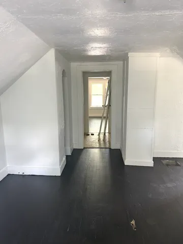 an empty room with wooden floor and windows with curtains
