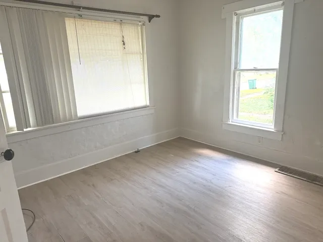 an empty room with wooden floor and windows