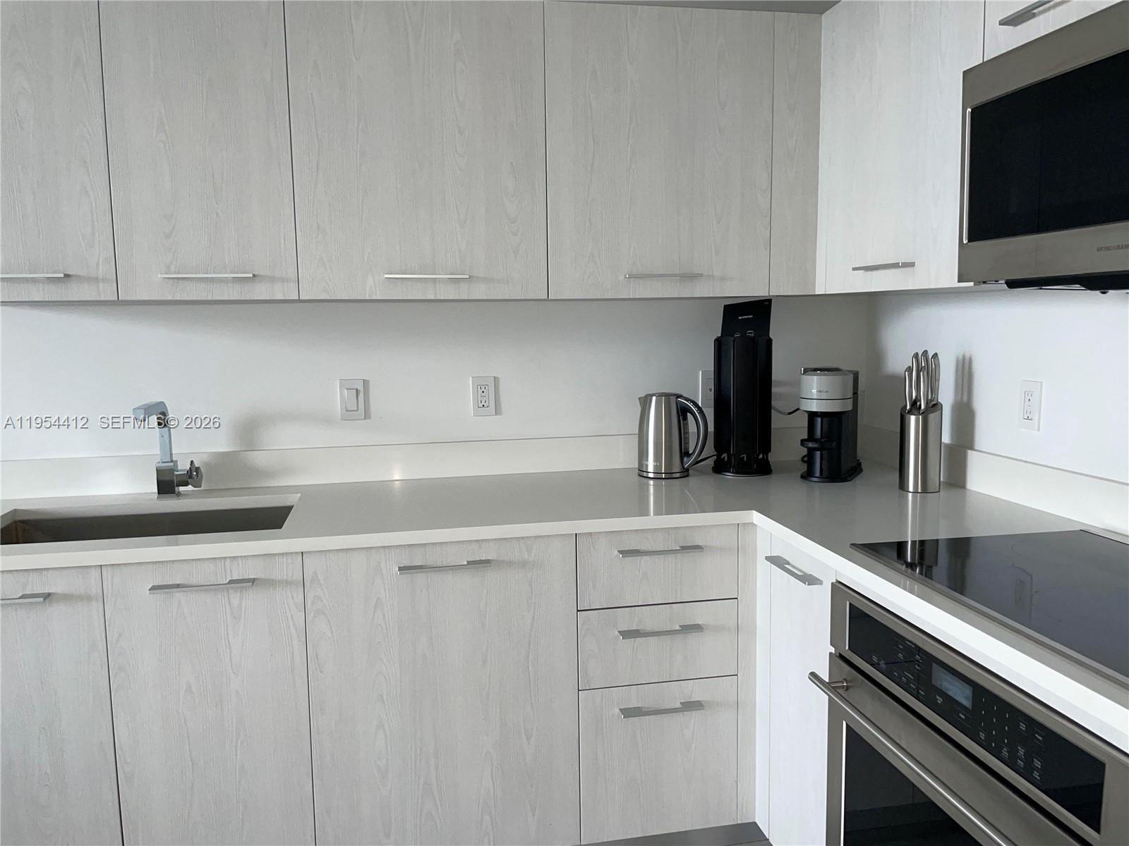 45 Southwest 9th Street, Unit 3910 Miami, FL 33130 - Photo 4 of 27 a kitchen with white cabinets and a sink