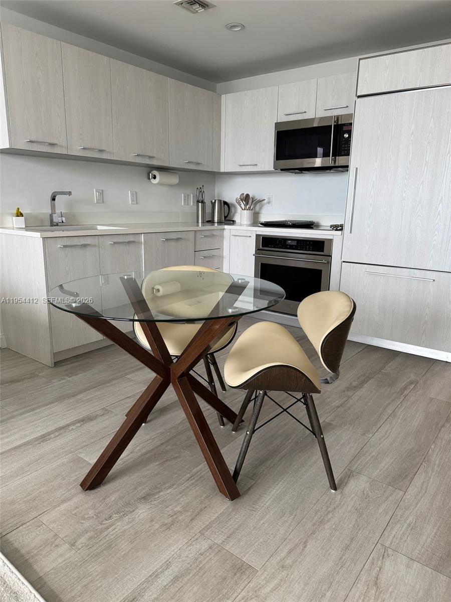 45 Southwest 9th Street, Unit 3910 Miami, FL 33130 - Photo 7 of 27 a kitchen with stainless steel appliances kitchen island granite countertop a table chairs sink and cabinets