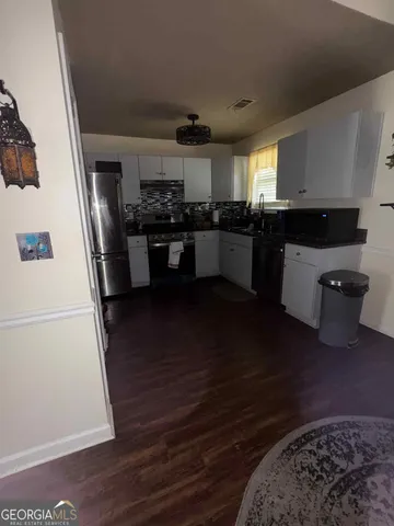 a kitchen with a refrigerator wooden floor and black cabinets