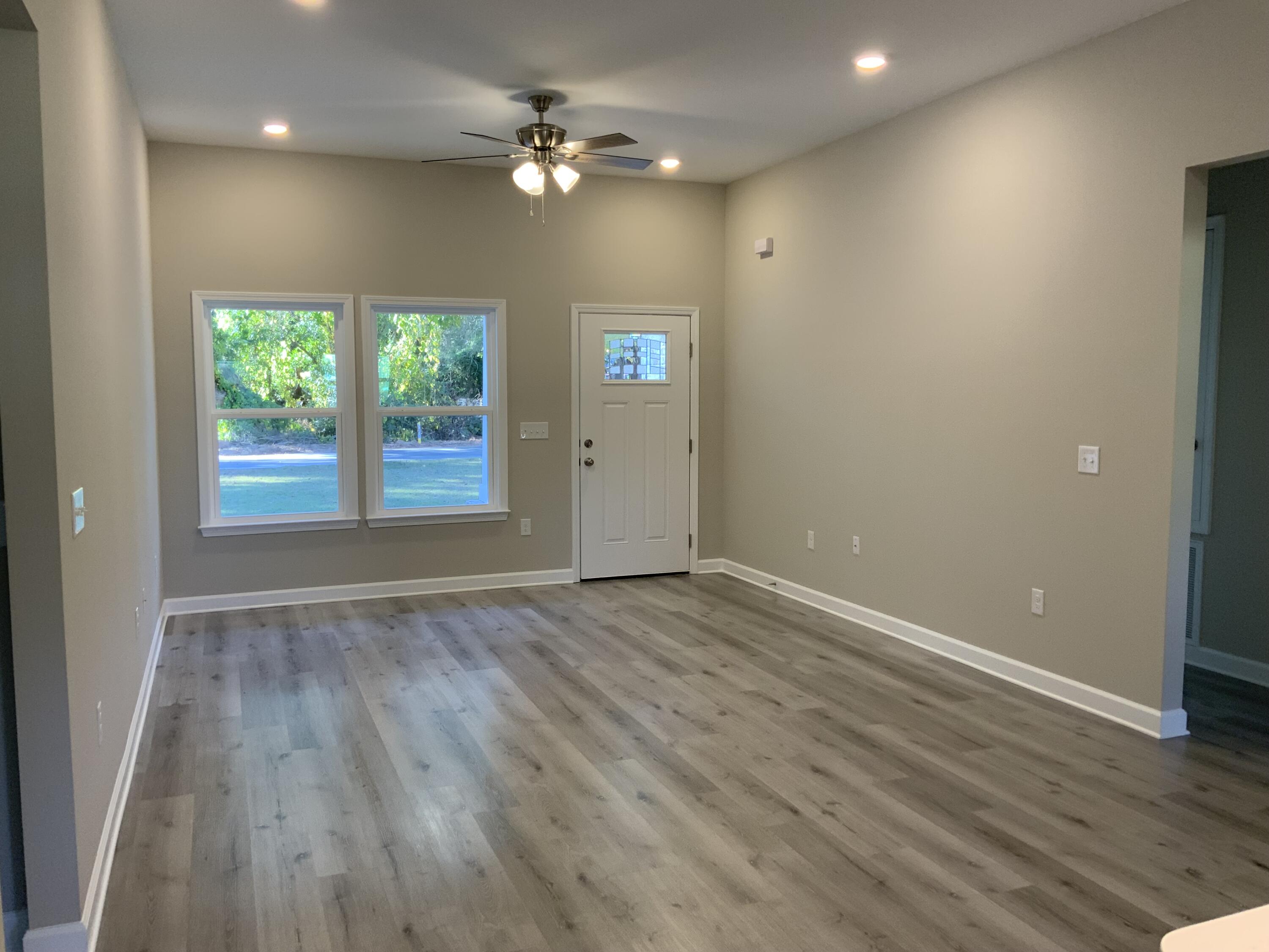 113 Shady Lane Crestview, FL 32536 - Photo 3 of 8 an empty room with wooden floor and windows
