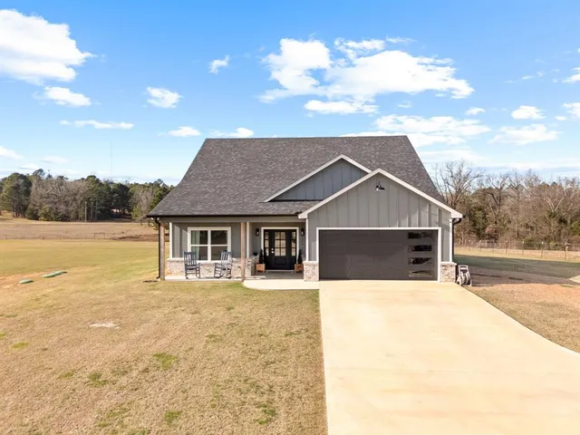 a front view of house with yard and trees in the background