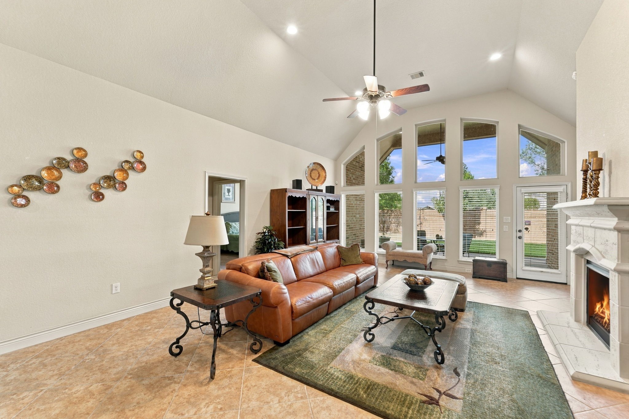 This spacious living room features vaulted ceilings and a wall of windows that flood the space with natural light. A cozy fireplace and easy access to the backyard make this the perfect gathering spot.