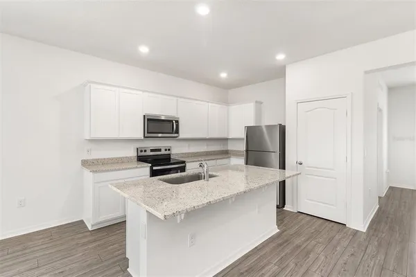 a kitchen with stainless steel appliances white cabinets and wooden floor
