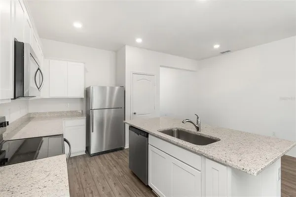 a kitchen that has a sink a refrigerator and a stove top oven