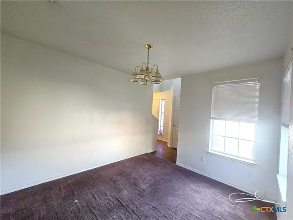 an empty room with wooden floor chandelier and windows