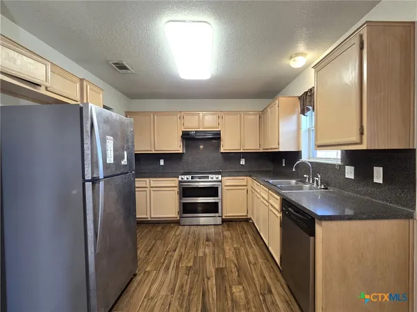a kitchen with a refrigerator a sink and dishwasher a oven with wooden floors