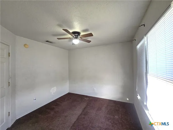 an empty room with a window and a fan