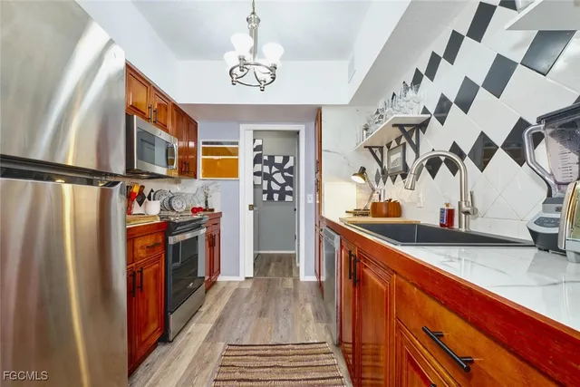 a kitchen with stainless steel appliances granite countertop a refrigerator a stove and a sink with wooden floor