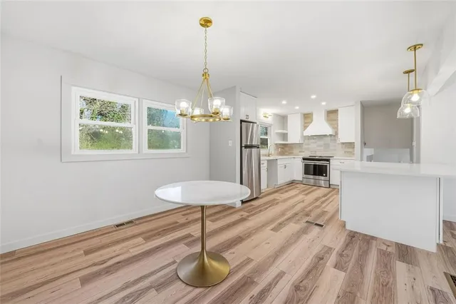 a room with stainless steel appliances kitchen island granite countertop furniture and a chandelier