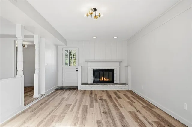 a view of an empty room with wooden floor fireplace and a window