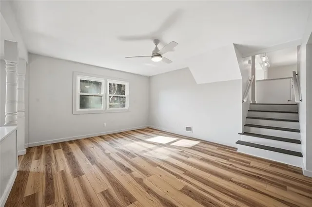 a view of empty room with wooden floor and fan