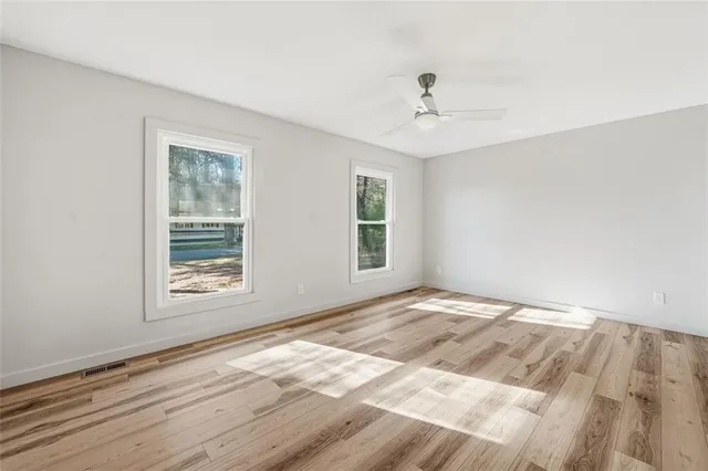 a view of an empty room with wooden floor and a window