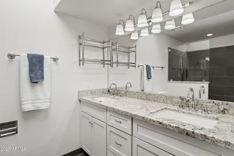 a bathroom with a granite countertop double vanity sink and mirror