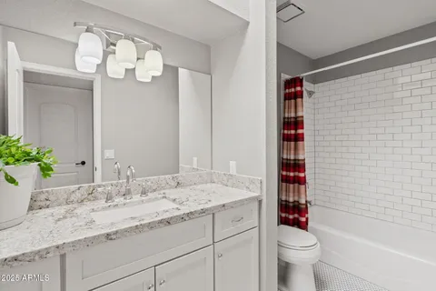 a bathroom with a granite countertop sink a toilet and shower