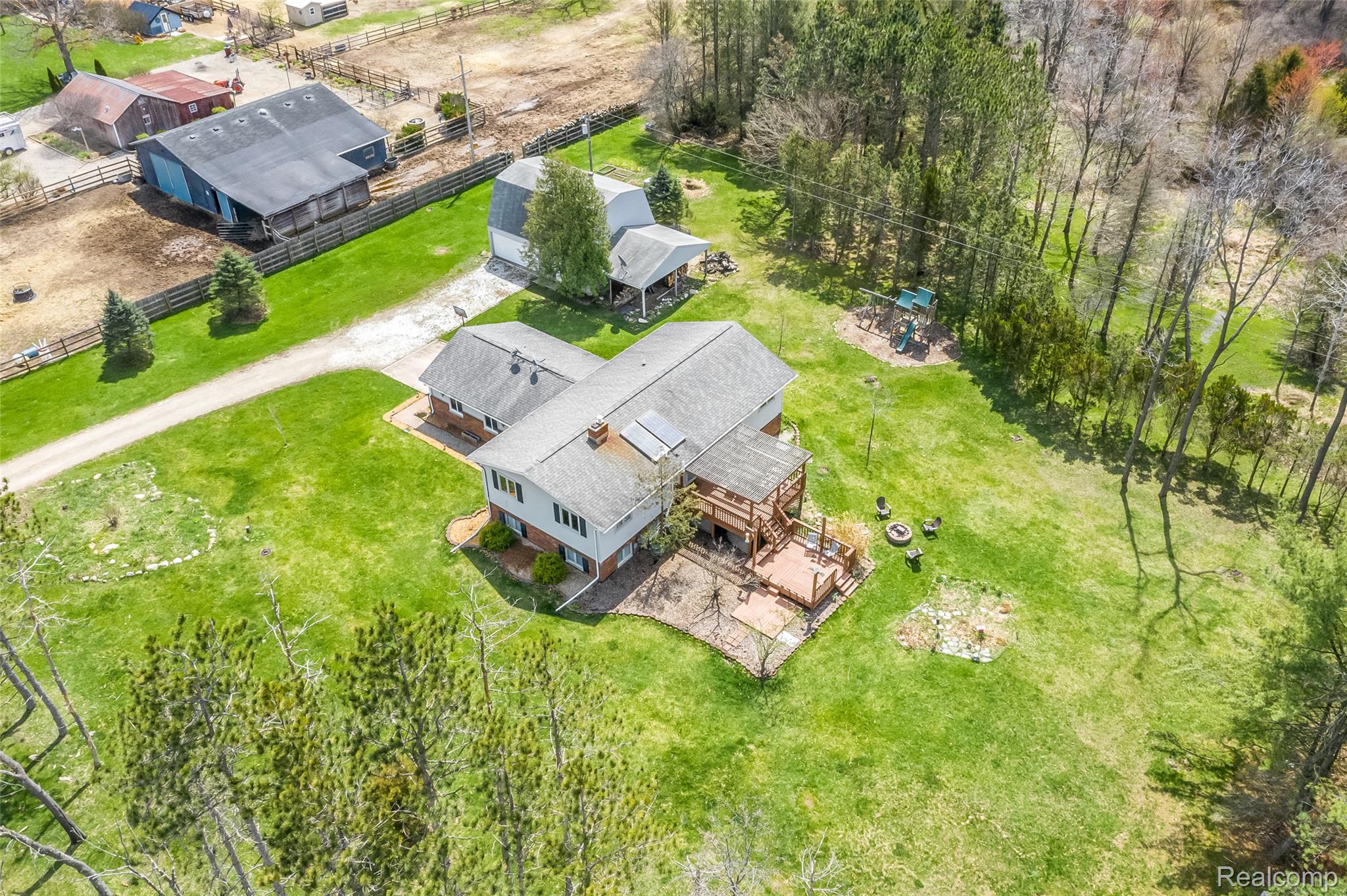 15395 Osius Road Chelsea, MI 48118 - Photo 46 of 55 Spacious property featuring a main residence with a multi-level deck, additional outbuildings, expansive green lawn, and mature trees