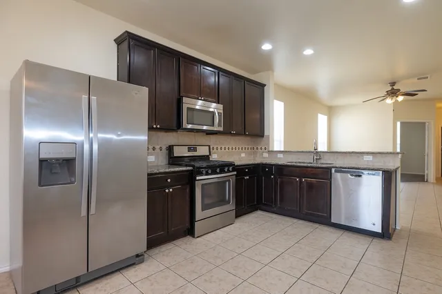 a kitchen with stainless steel appliances granite countertop a refrigerator and a stove top oven