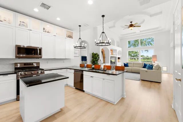 a kitchen with stainless steel appliances granite countertop a sink a stove and a wooden floors