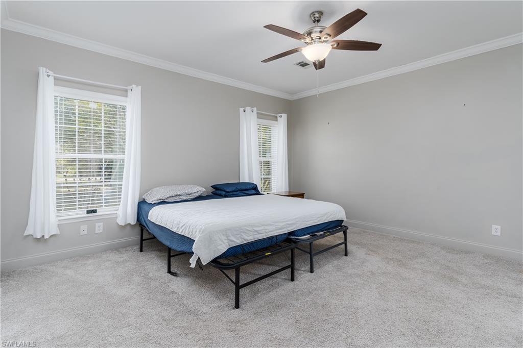 104 Rookery Road Naples, FL 34114 - Photo 11 of 32 a bed sitting in a room and with a ceiling fan