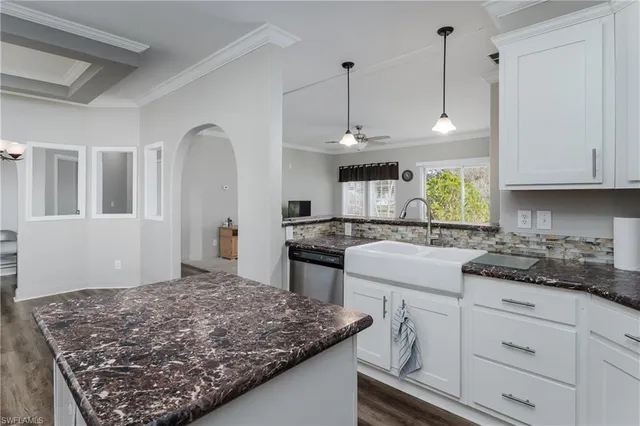 a kitchen with stainless steel appliances granite countertop a stove a sink and white cabinets