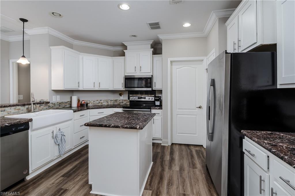 104 Rookery Road Naples, FL 34114 - Photo 8 of 32 a kitchen with stainless steel appliances granite countertop a refrigerator a sink dishwasher a stove and white cabinets with wooden floor