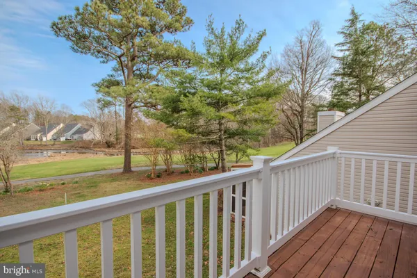a view of a wooden deck with trees in front of house