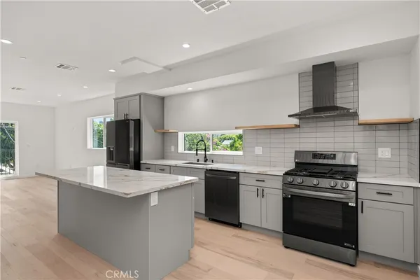 a kitchen with stainless steel appliances granite countertop a stove top oven a sink and a refrigerator