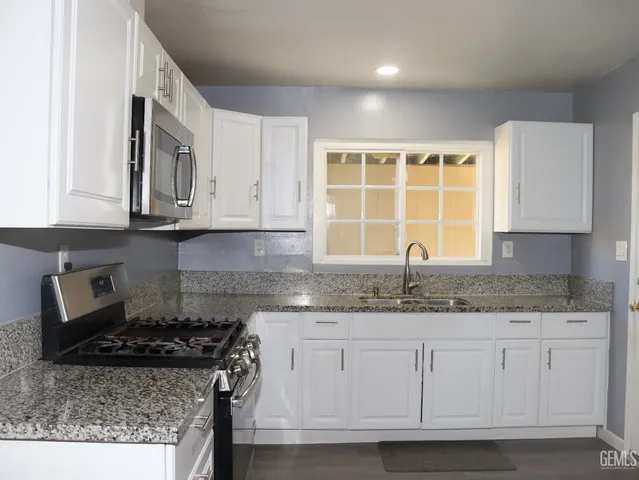 a kitchen with stainless steel appliances granite countertop a sink stove and cabinets