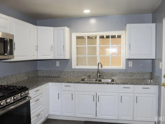 a kitchen with granite countertop white cabinets and stainless steel appliances