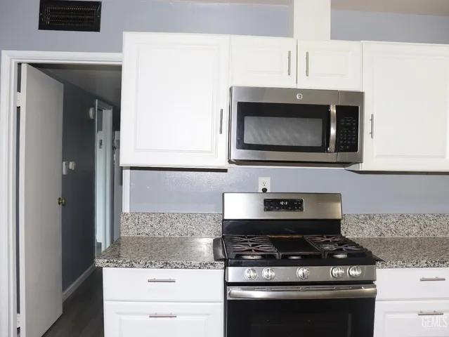 a kitchen with granite countertop a stove and a microwave