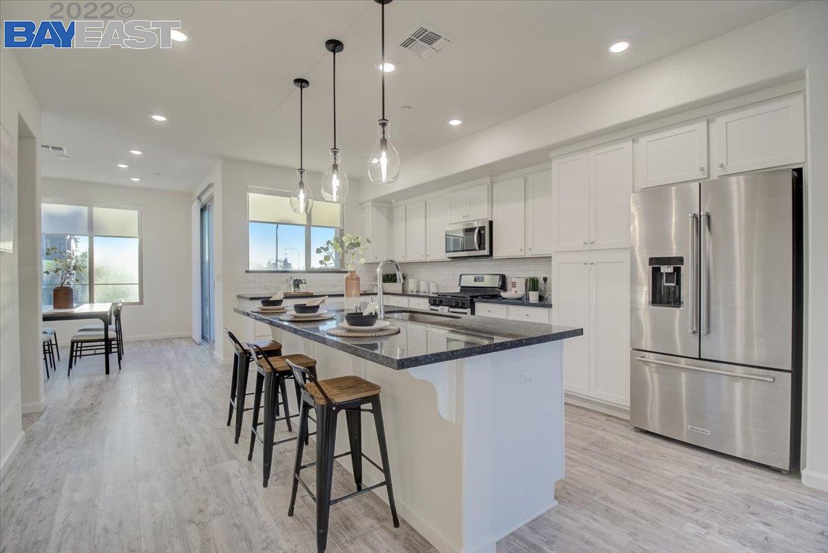 a kitchen with stainless steel appliances granite countertop a table chairs refrigerator and sink