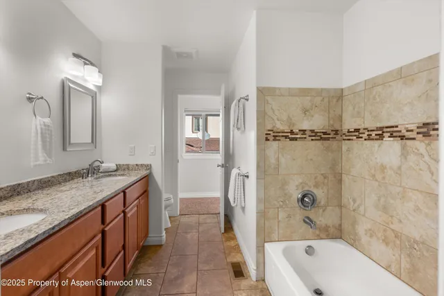 a bathroom with a granite countertop sink a mirror a bathtub and shower