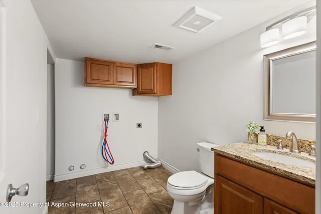 a bathroom with a granite countertop sink vanity mirror and toilet