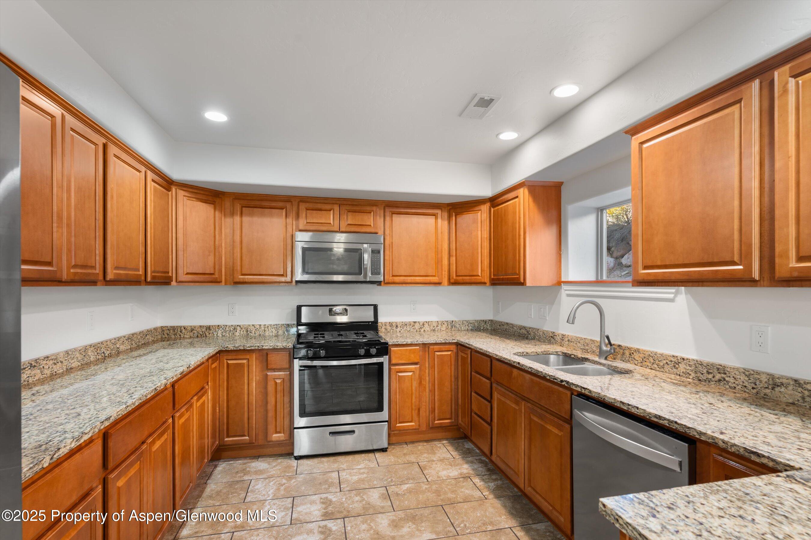 200 Castle Ridge Drive New Castle, CO 81647 - Photo 6 of 24 a kitchen with stainless steel appliances granite countertop wooden cabinets a sink and a stove