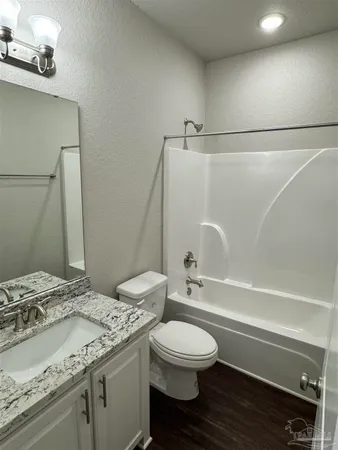 a bathroom with a granite countertop bathtub shower sink vanity mirror and toilet