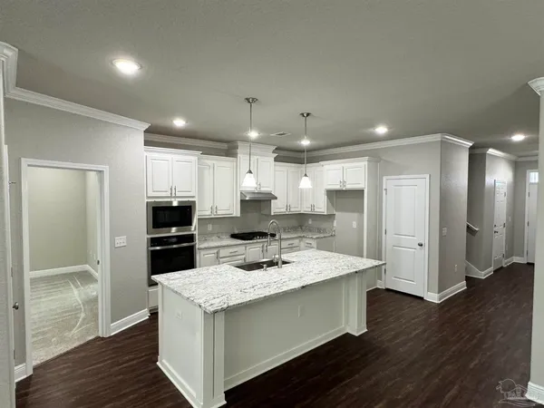 a kitchen with a appliances a sink cabinets and wooden floor