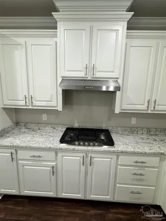 a kitchen with granite countertop white cabinets and a stove