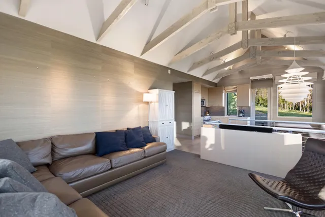 a living room with stainless steel appliances furniture a rug and a kitchen view