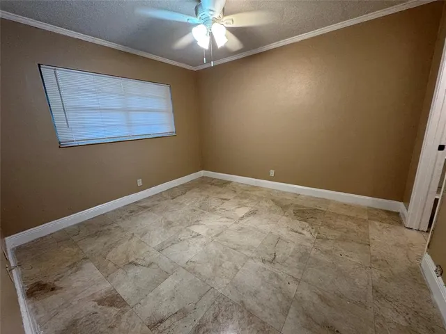 an empty room with a chandelier fan and windows