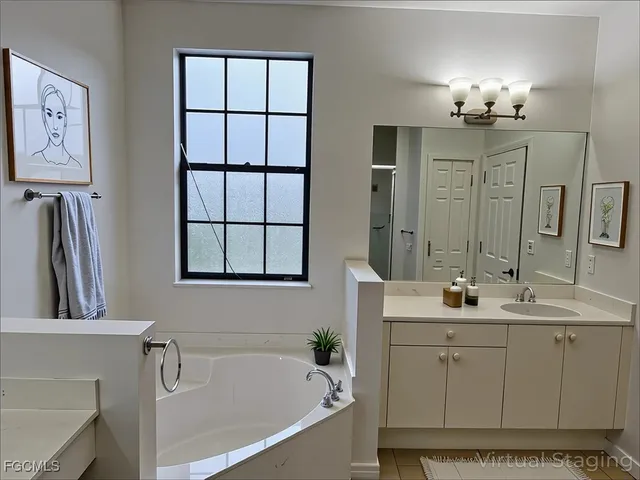 a bathroom with a double vanity sink a mirror a bathtub and window