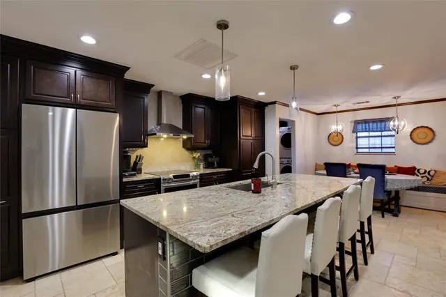 a kitchen with stainless steel appliances granite countertop a kitchen island a stove a refrigerator a oven a sink a dining table and chairs with wooden floor