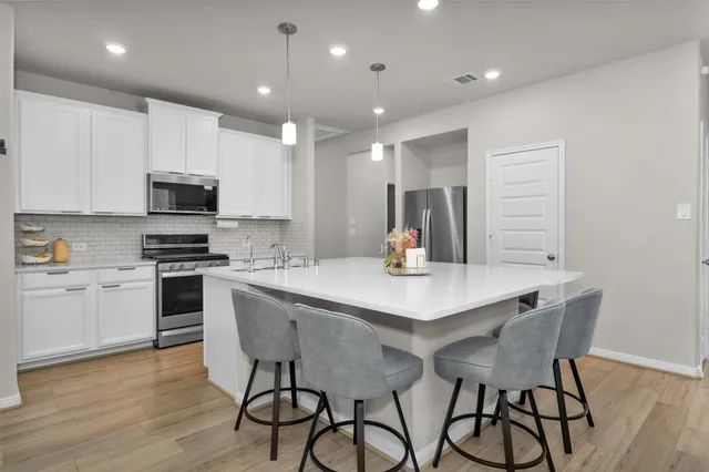 a kitchen with a table chairs microwave and cabinets