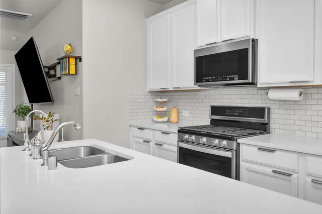 a kitchen with stainless steel appliances a stove a microwave a sink and cabinets