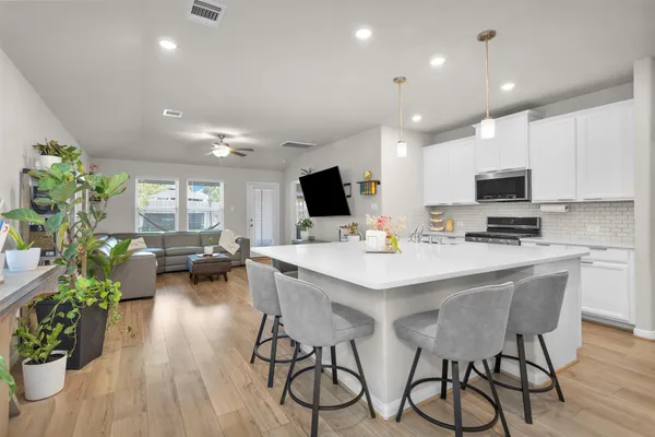 a view of kitchen with microwave stove refrigerator dining table and chairs