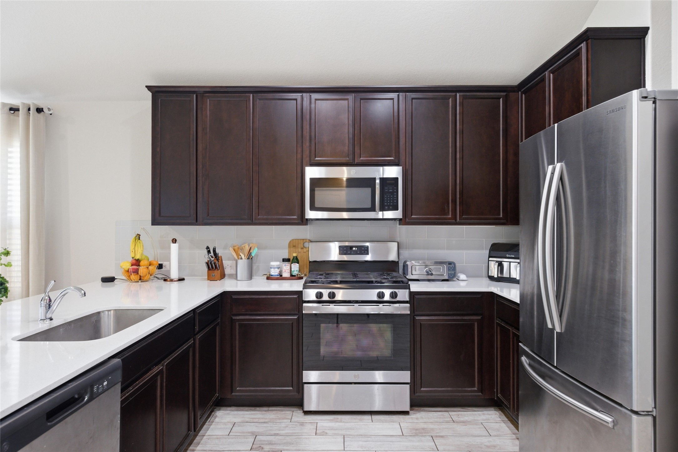 269 Gaida Loop Georgetown, TX 78628 - Photo 6 of 20 Kitchen featuring stainless steel appliances, dark wood finish cabinets, and backsplash