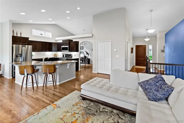 a living room with stainless steel appliances kitchen island granite countertop a couch a dining table and chairs