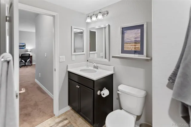 a bathroom with a toilet sink vanity and mirror