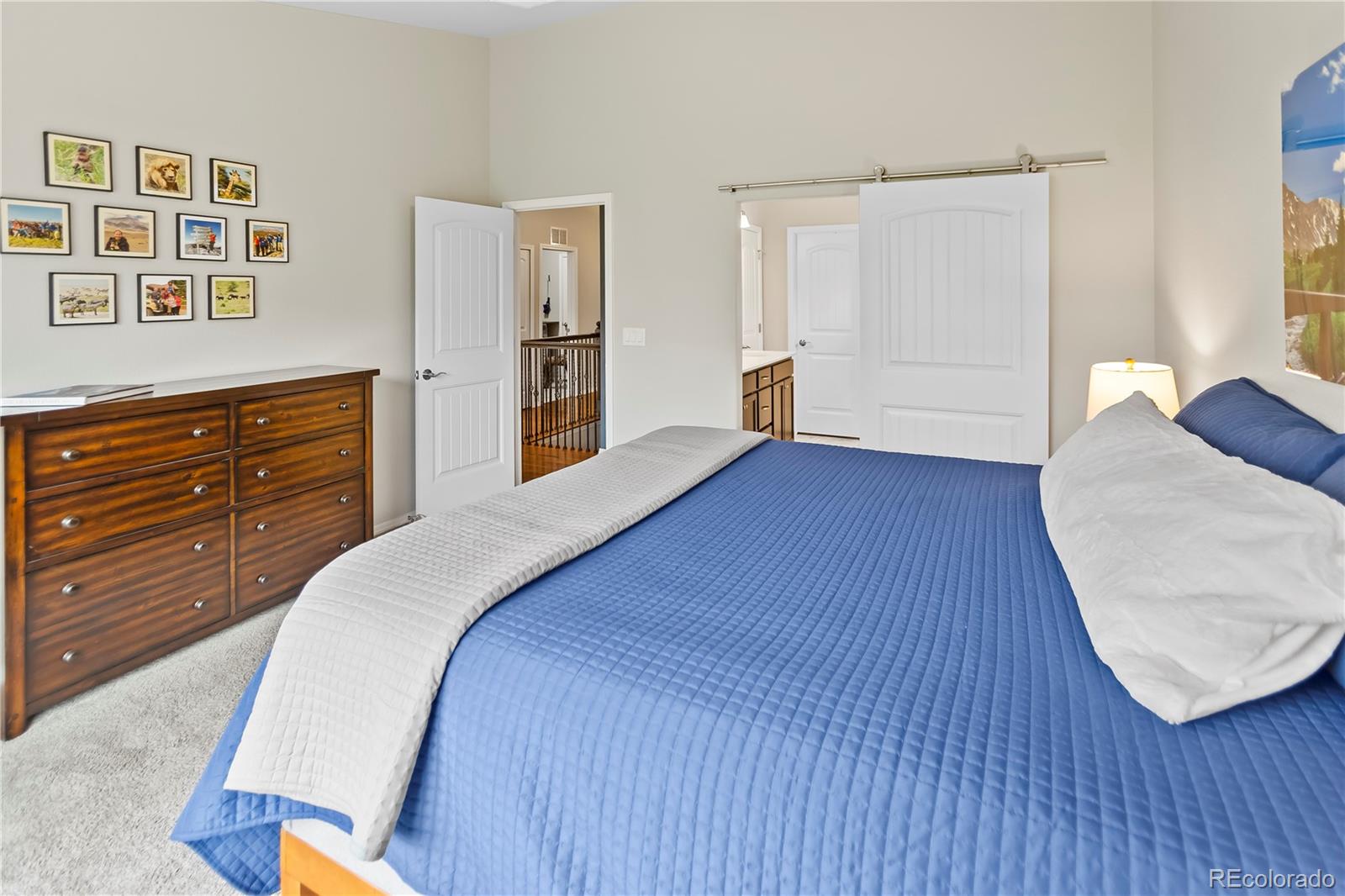 10687 Hidden Brook Circle Colorado Springs, CO 80908 - Photo 19 of 36 a spacious bedroom with a bed and a wooden floor
