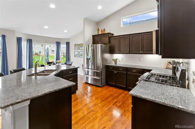 a kitchen with stainless steel appliances granite countertop a sink a stove and a refrigerator